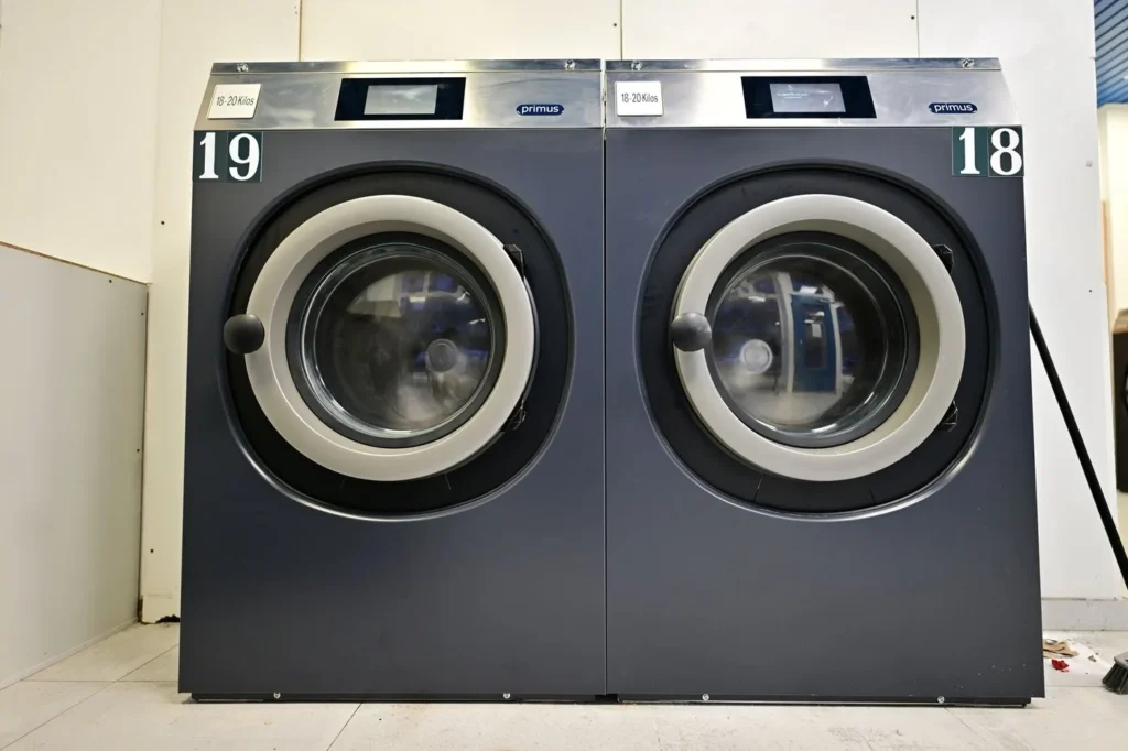 Deux grandes machines Primus grises, numéros 18 et 19, étiquette 18-20 kilos